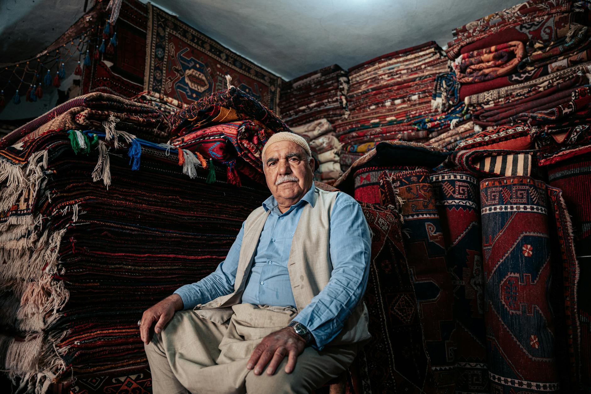 Man Sitting with Carpets behind