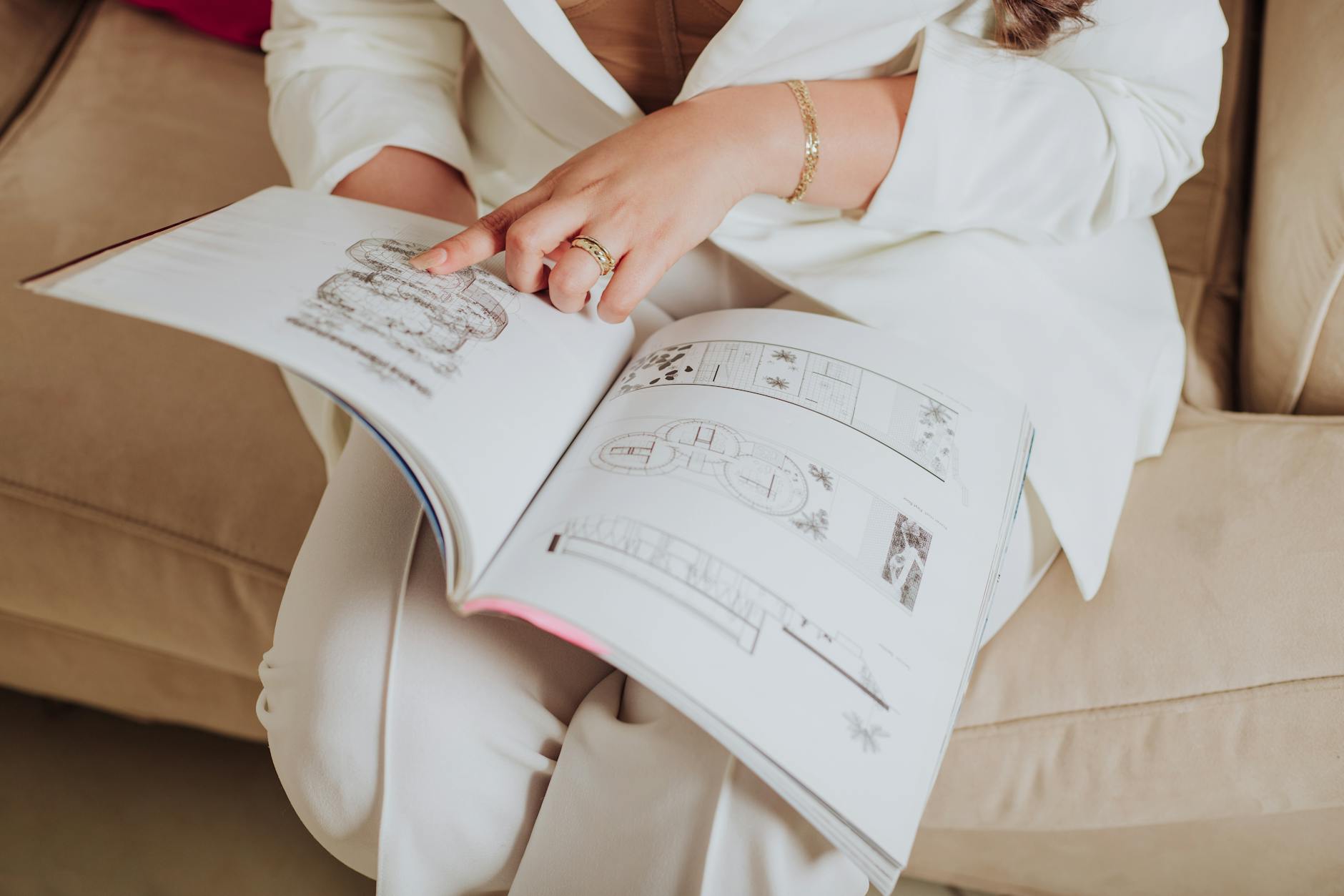 Close-up of an Elegant Woman Sitting on a Sofa Pointing at an Illustration in a Book