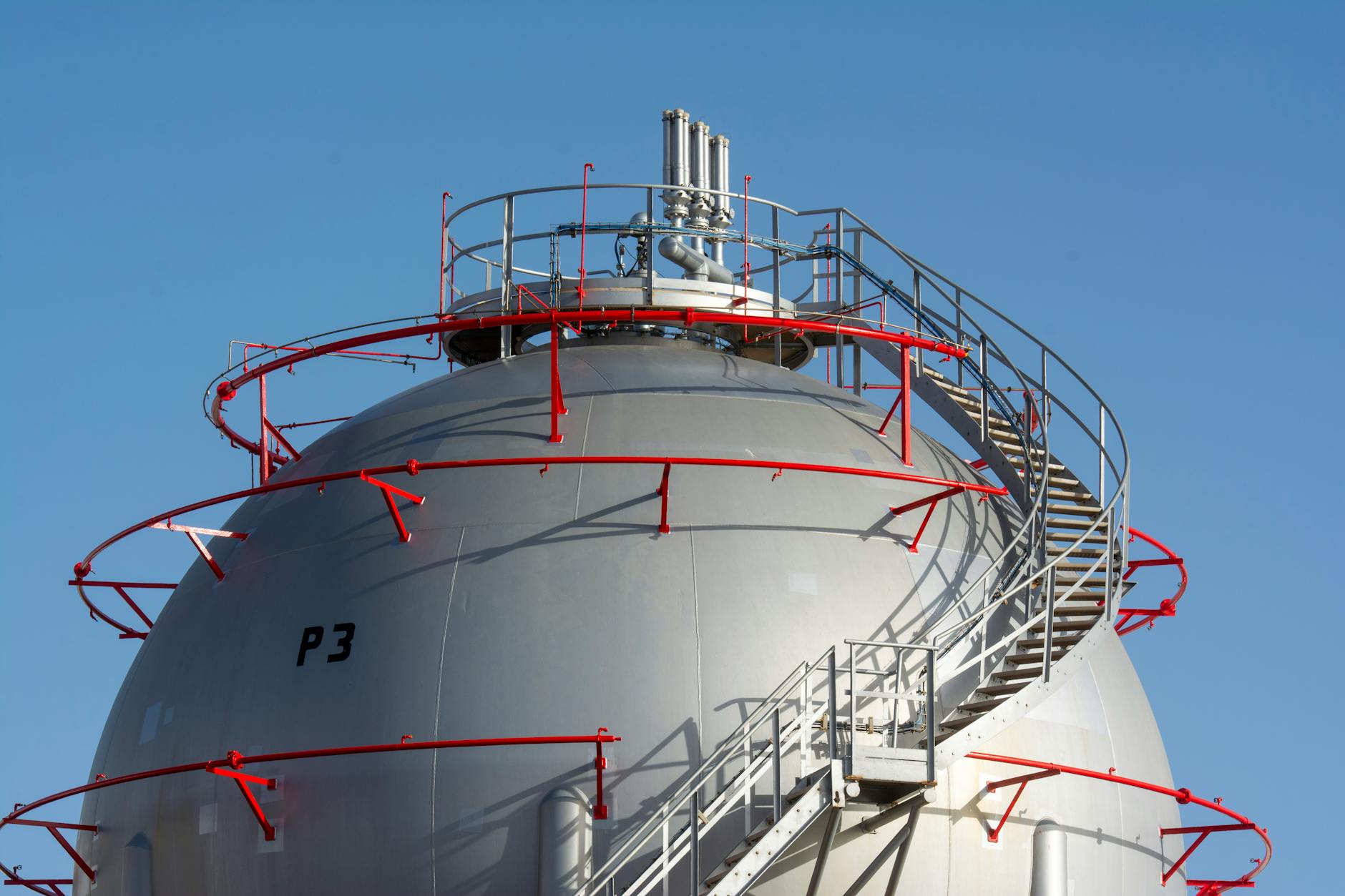 A large steel tank with red stairs and a blue sky