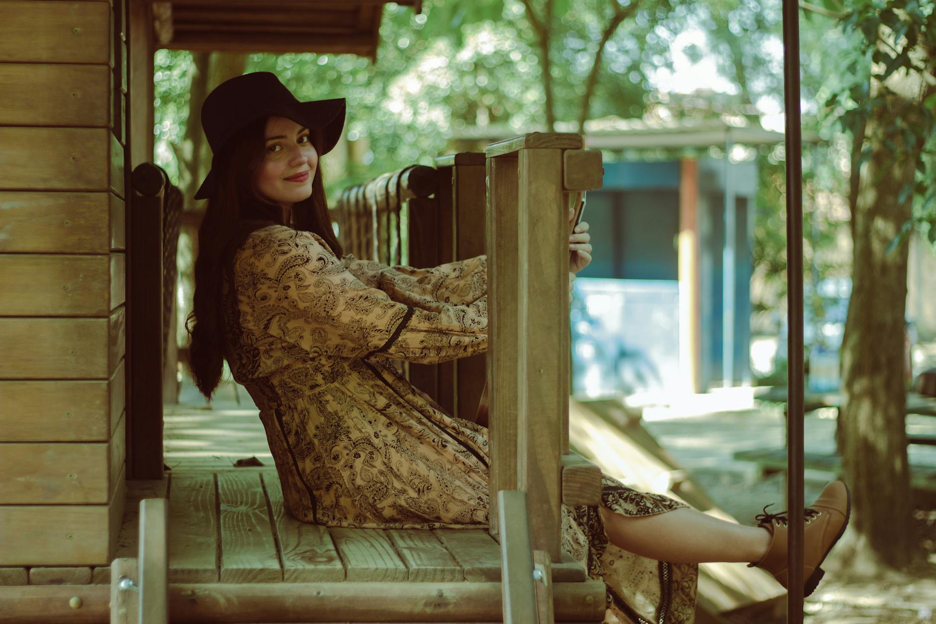 Young Brunette Woman in Dress Sitting on Terrace of Cottage