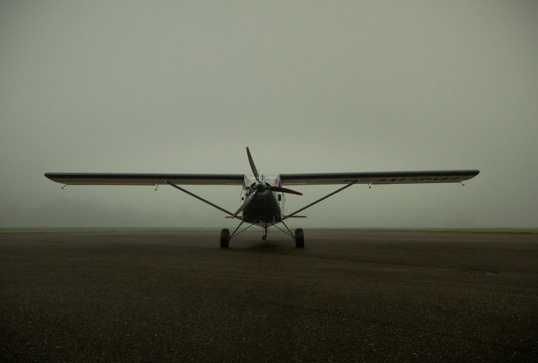 A small aircraft positioned on a foggy runway, creating a moody aviation scene.