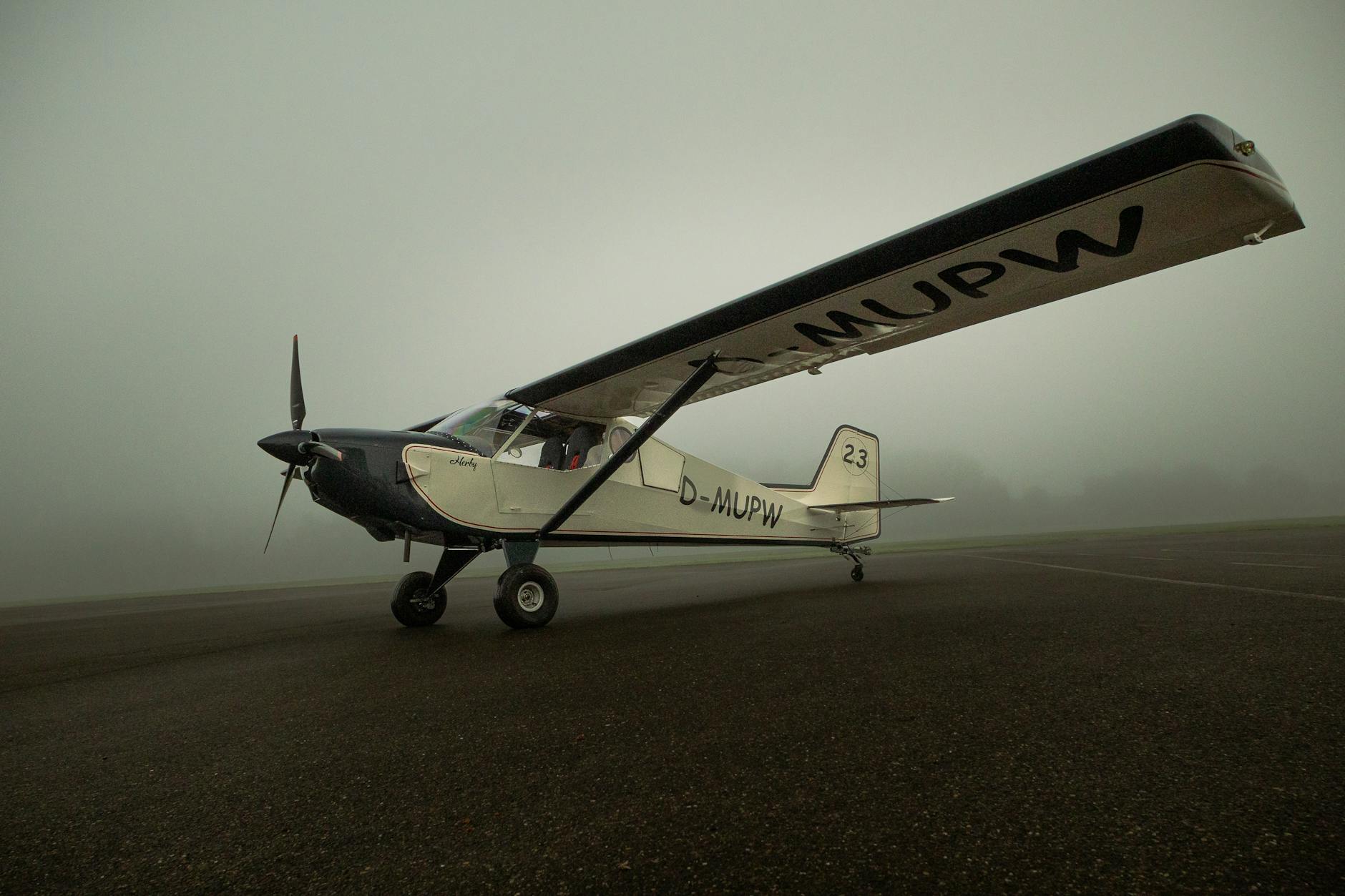 A small aircraft parked on a foggy runway at dawn, showcasing aviation tranquility.