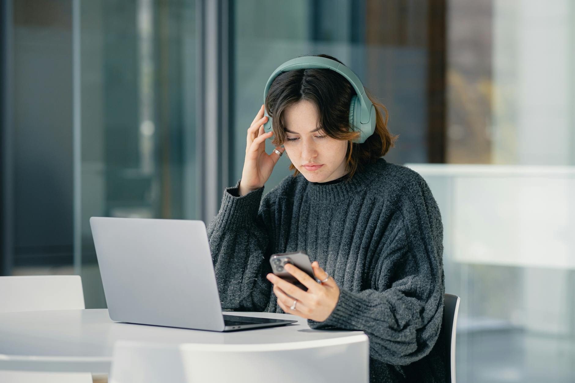 Focused young woman using laptop and smartphone