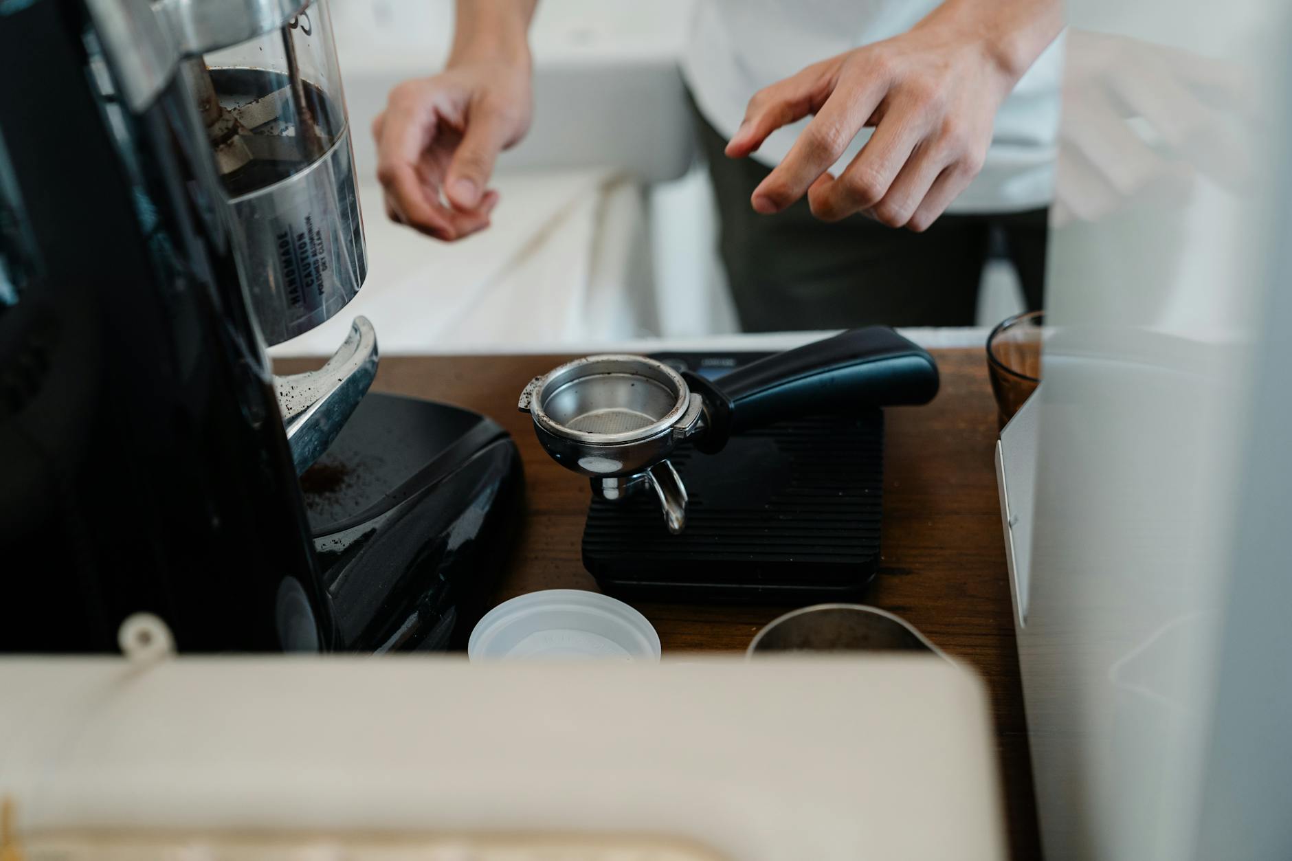 Crop barista preparing coffee by using portafilter