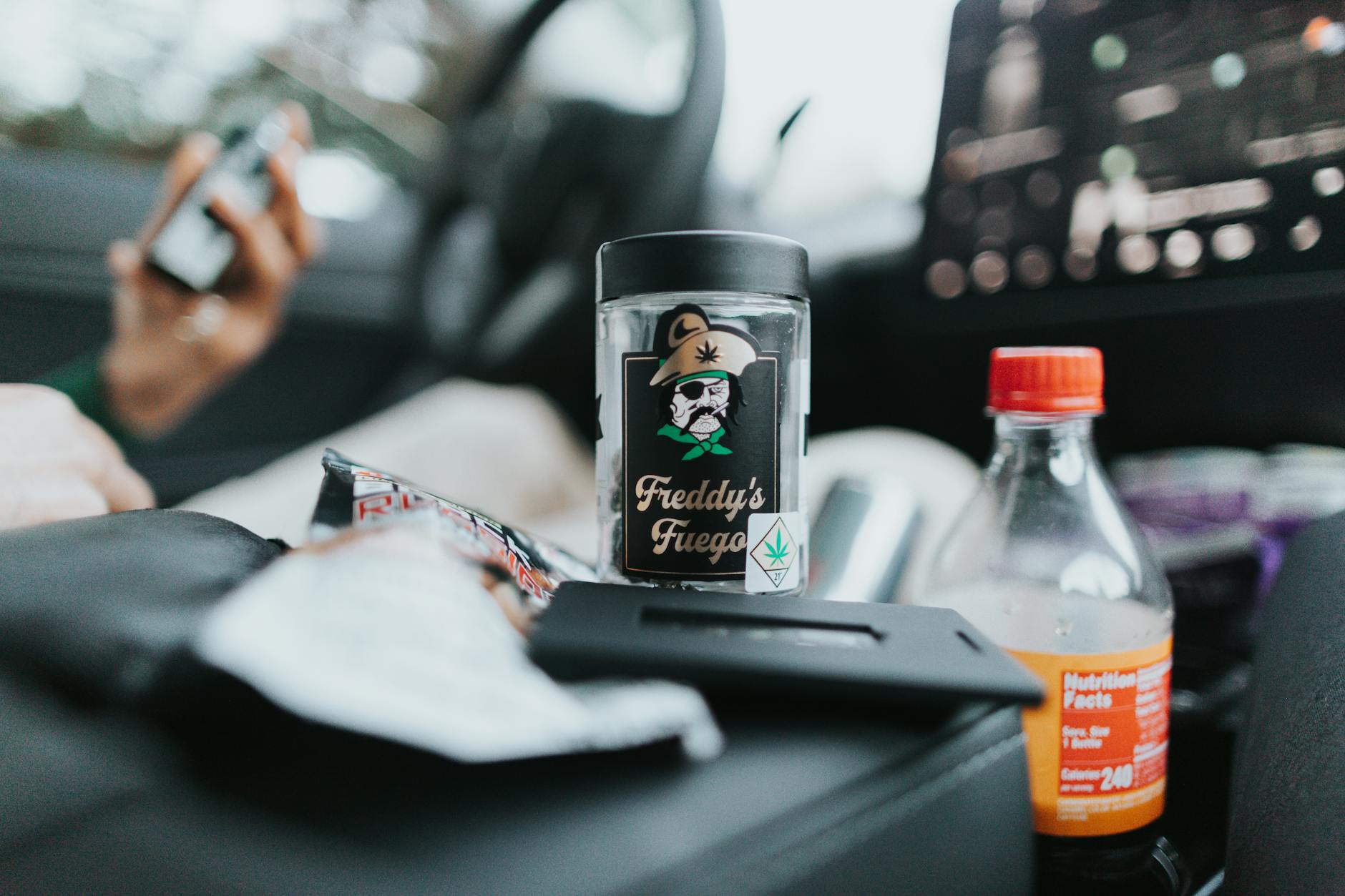 Glass Bottle of Cannabis Beside a Drink in Plastic Bottle