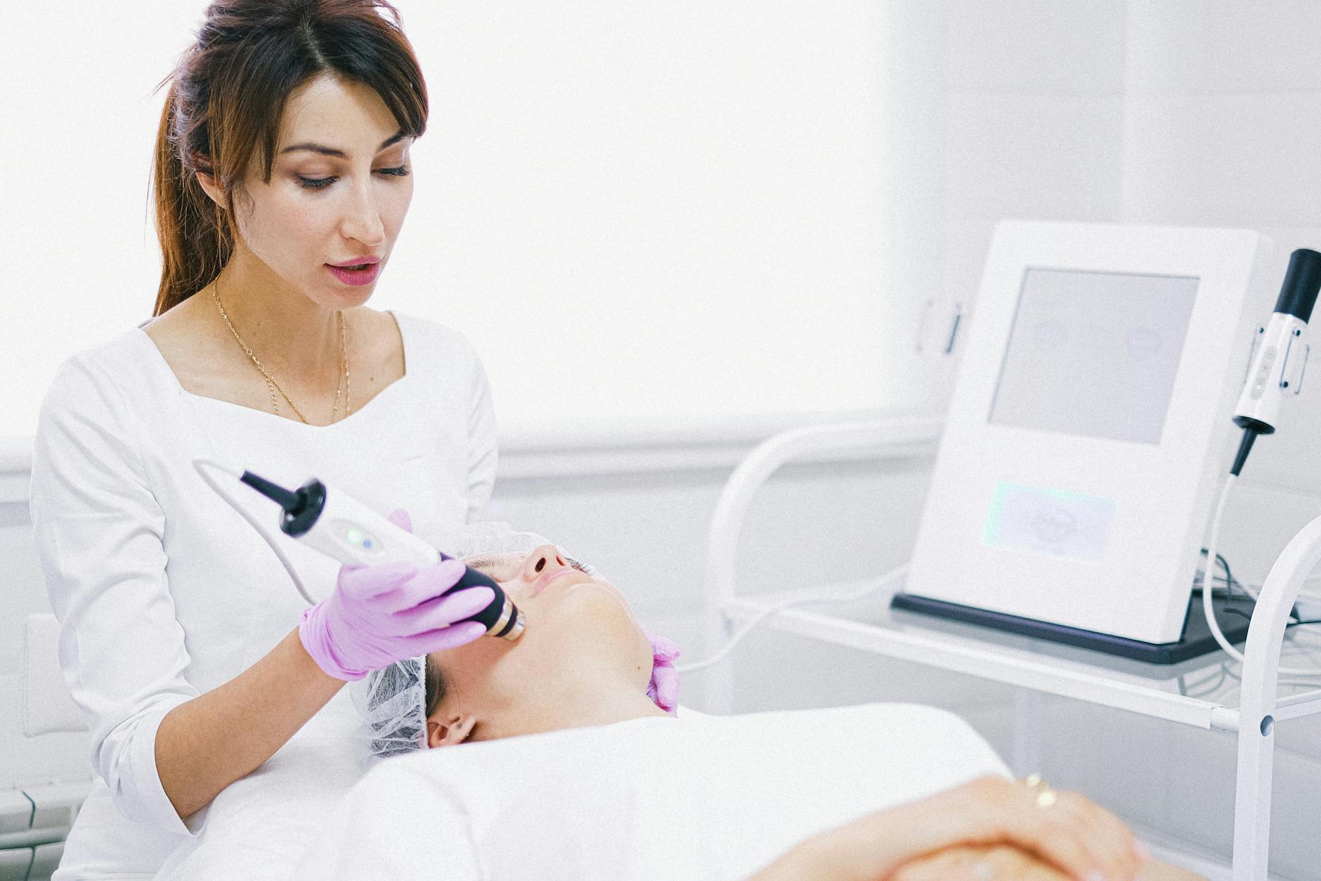 A Woman in White Shirt Lying on Bed while having Facial Treatment