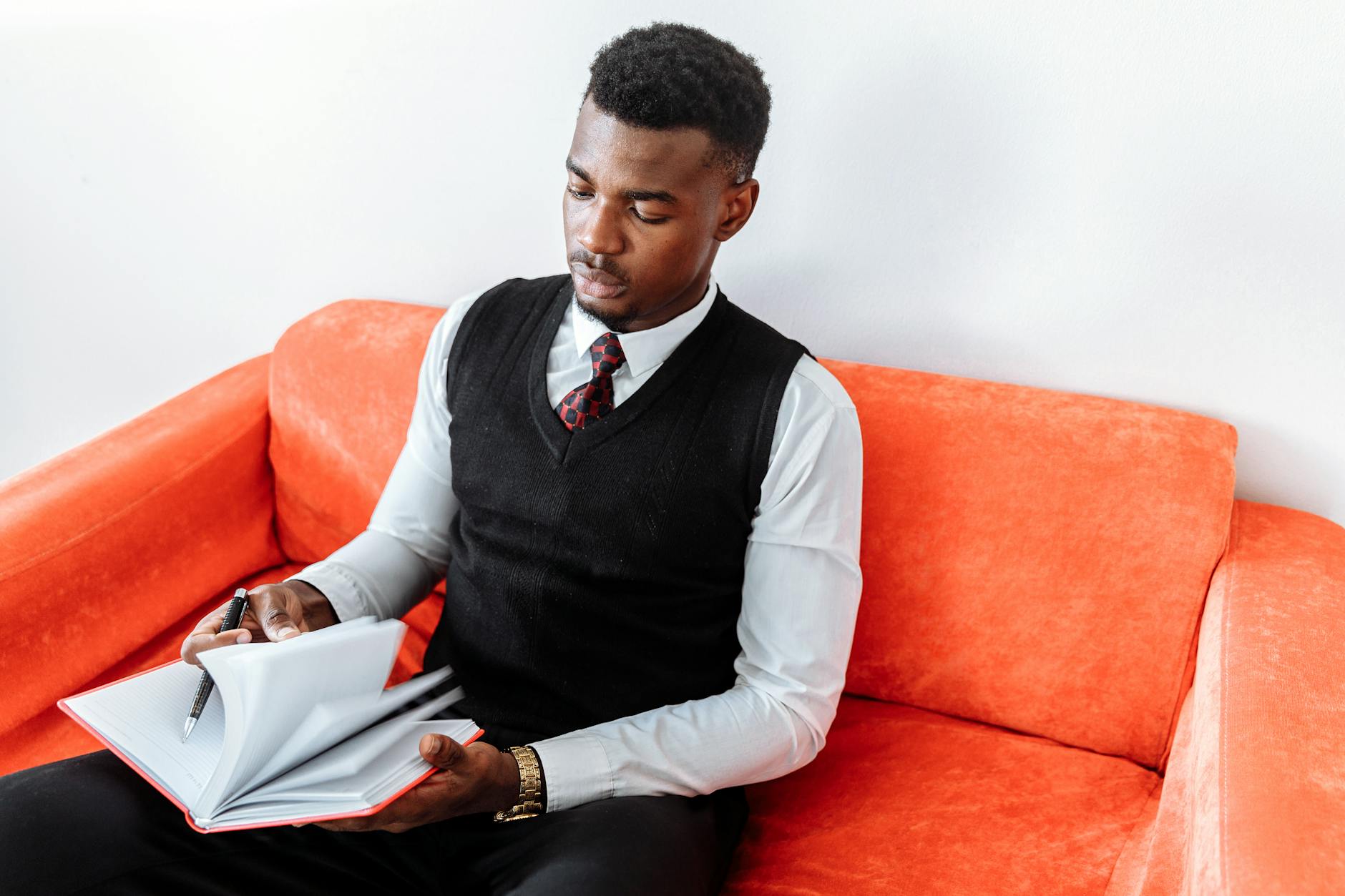 Man in Black Vest and White Dress Shirt Sitting on Orange Sofa