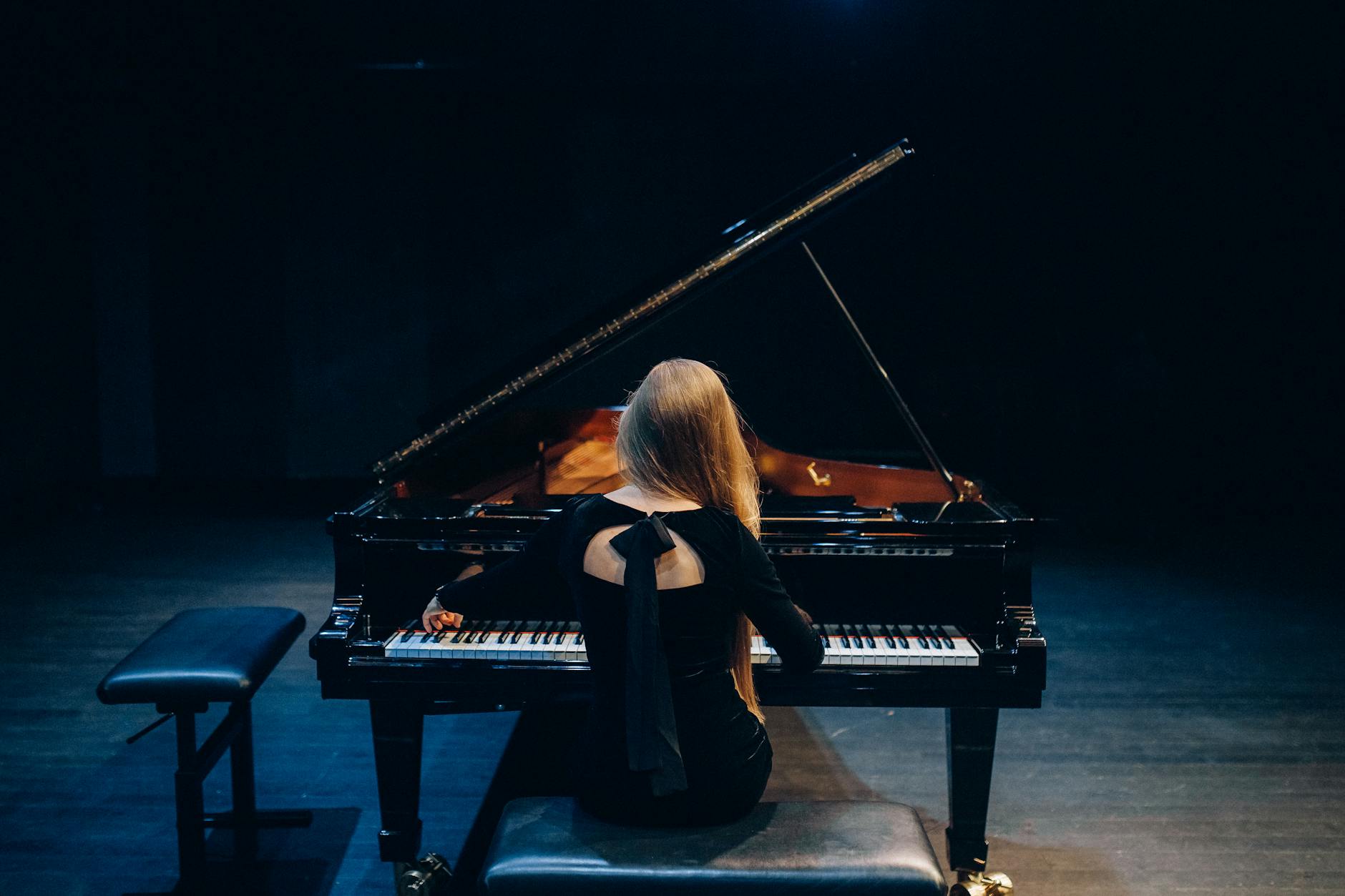 Woman in Black Long Sleeve Shirt Playing Grand Piano