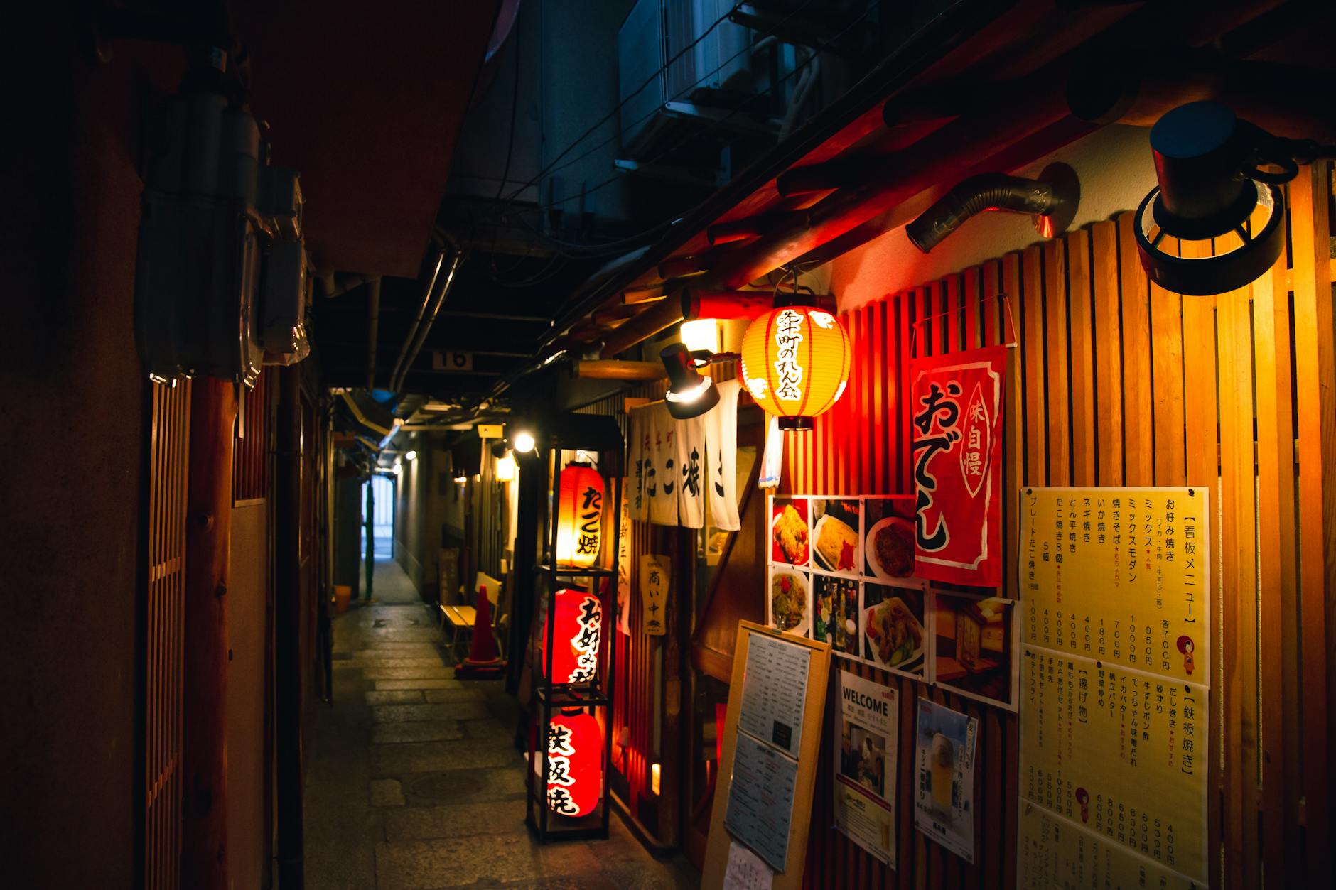 Narrow street with traditional Japanese izakaya bars decorated with hieroglyphs and traditional red lanterns in evening