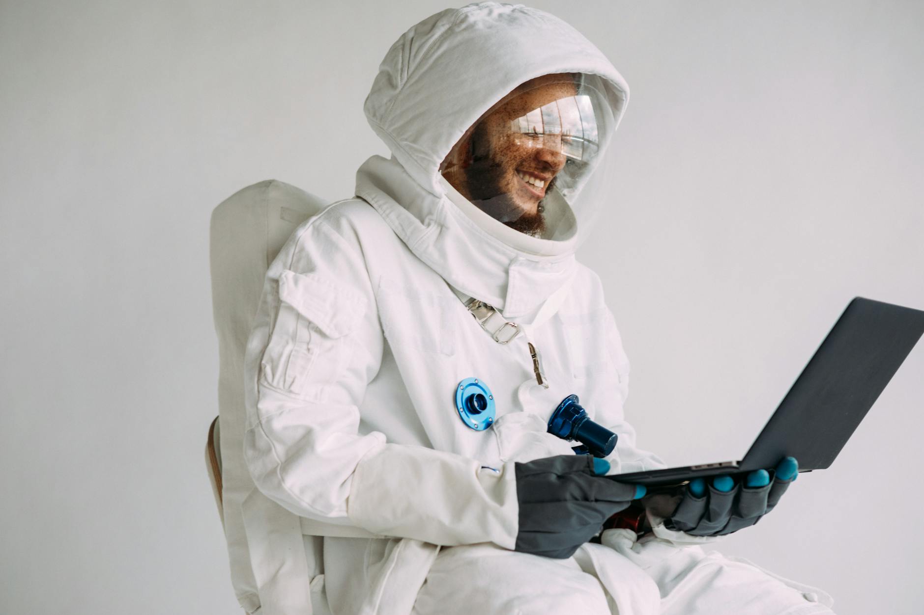 Image of a man wearing a space suit holding a laptop