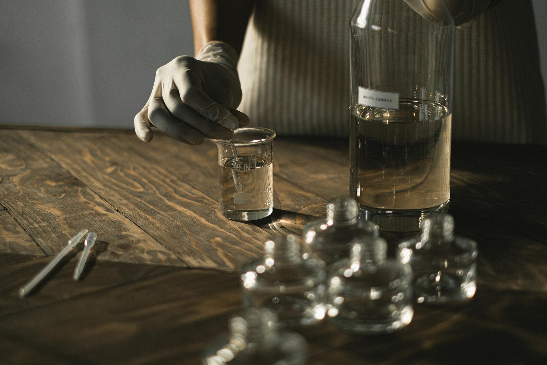 anonymous female in latex gloves making fluid for perfume