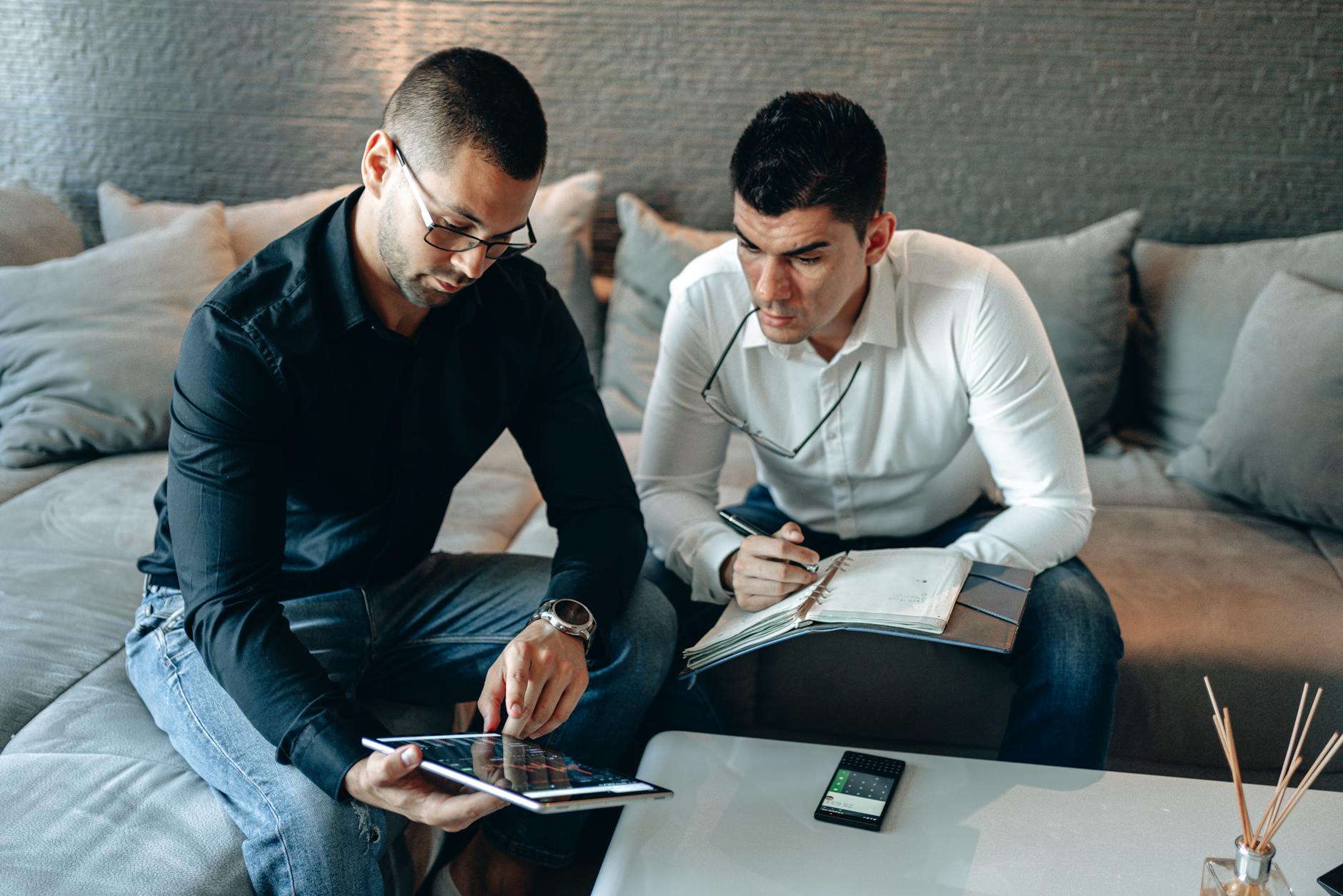 Man in Black Suit Jacket Sitting Beside Man in White Long Sleeve Shirt