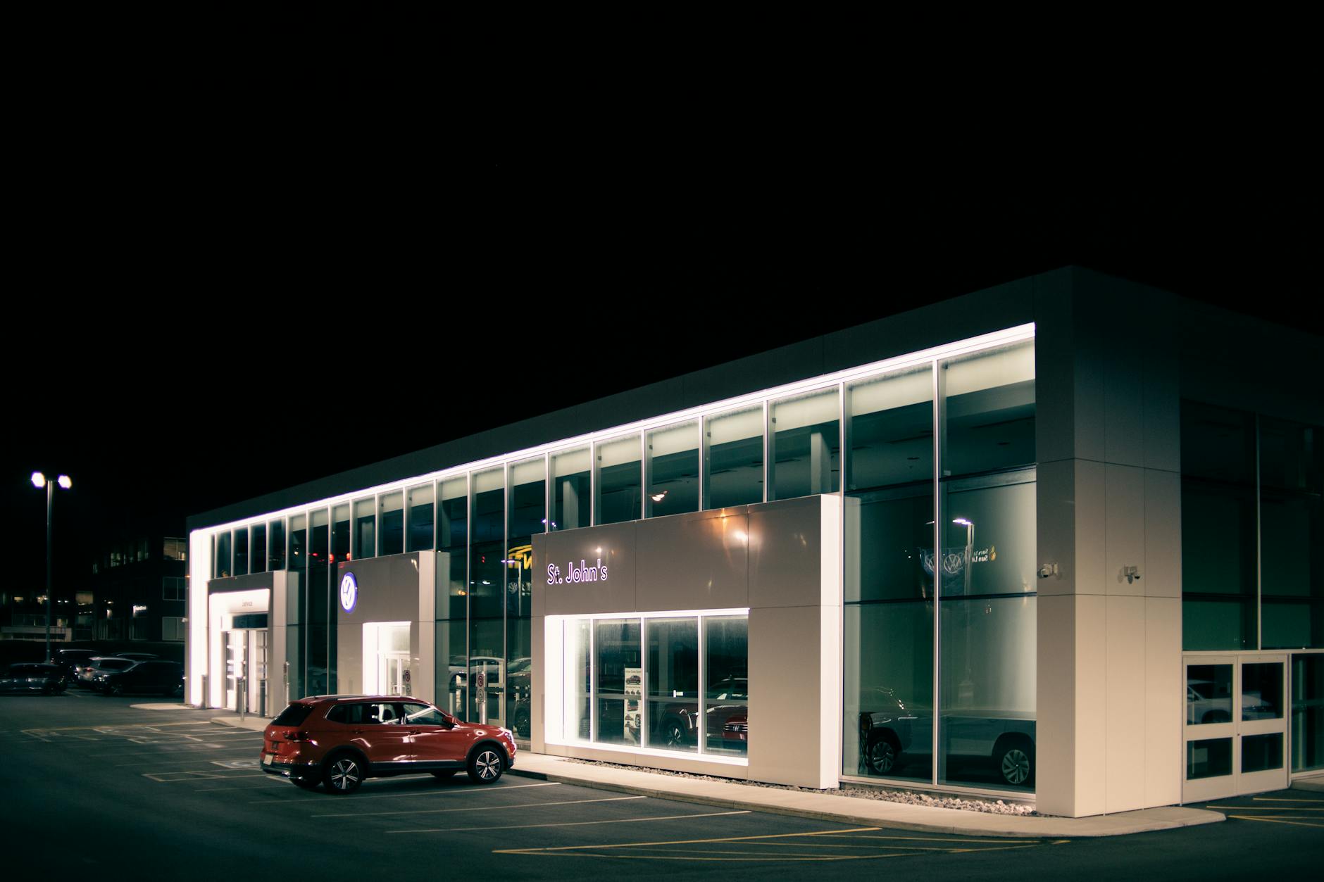 Off road car parked near entrance of shop with luminous lights at dark night