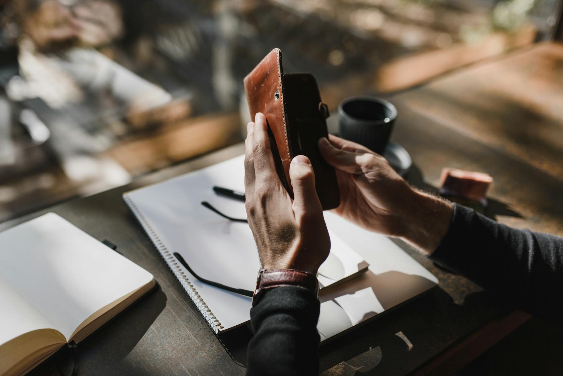 Man Hands Holding Wallet over Notebook on Table