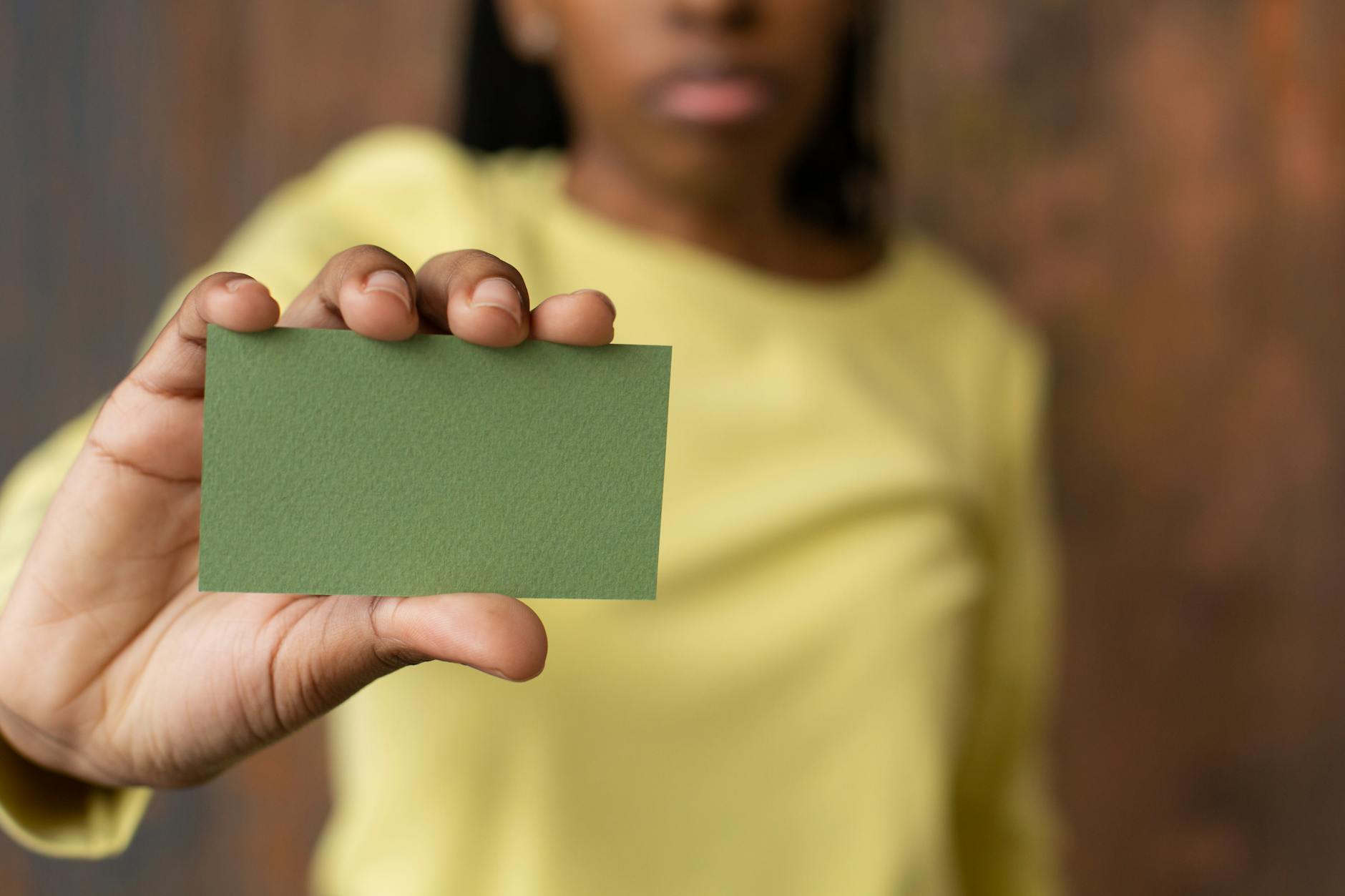 Crop black woman with green blank business card