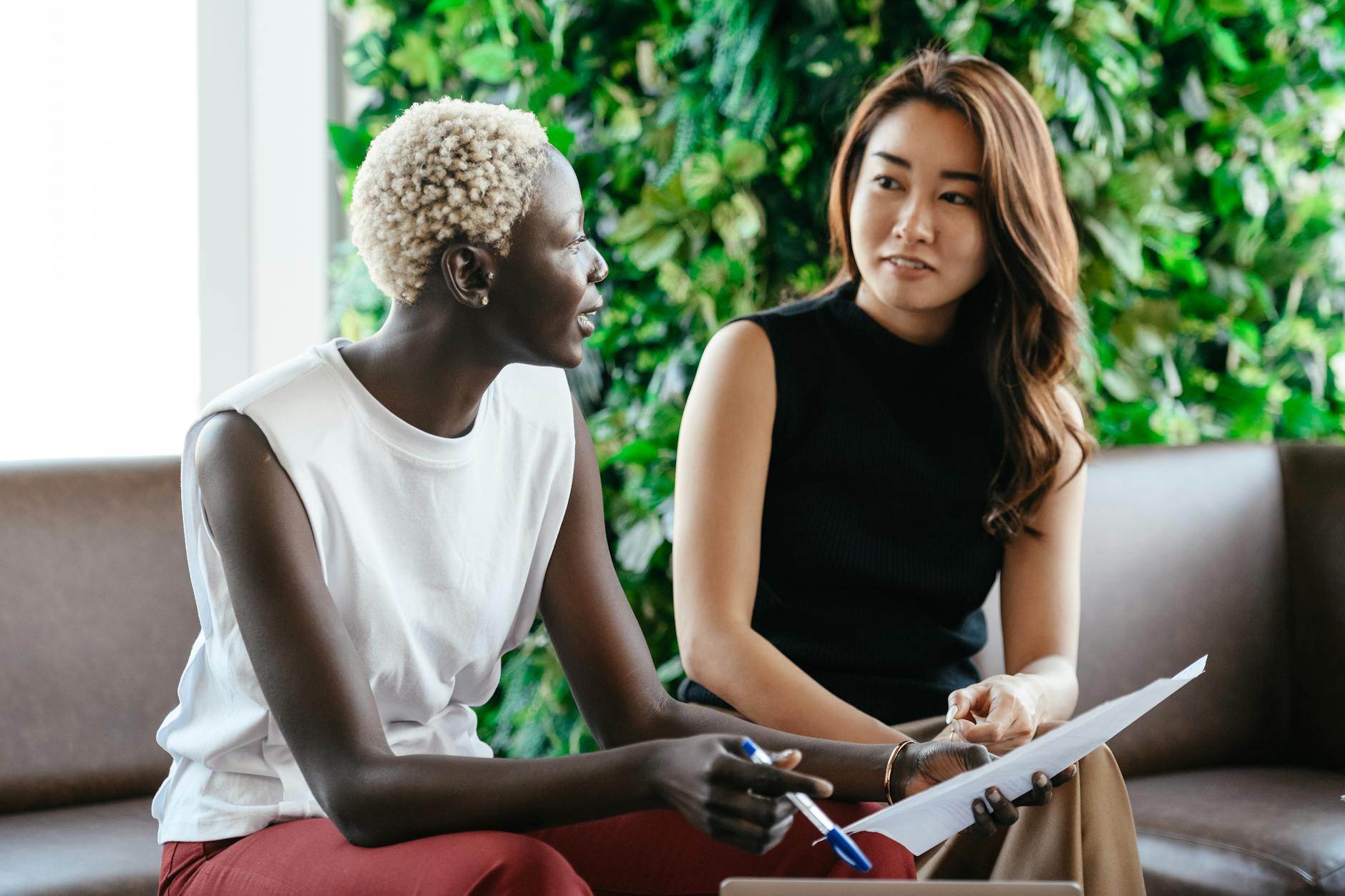 Diverse women talking about job while discussing contract and looking at each other in conference hall