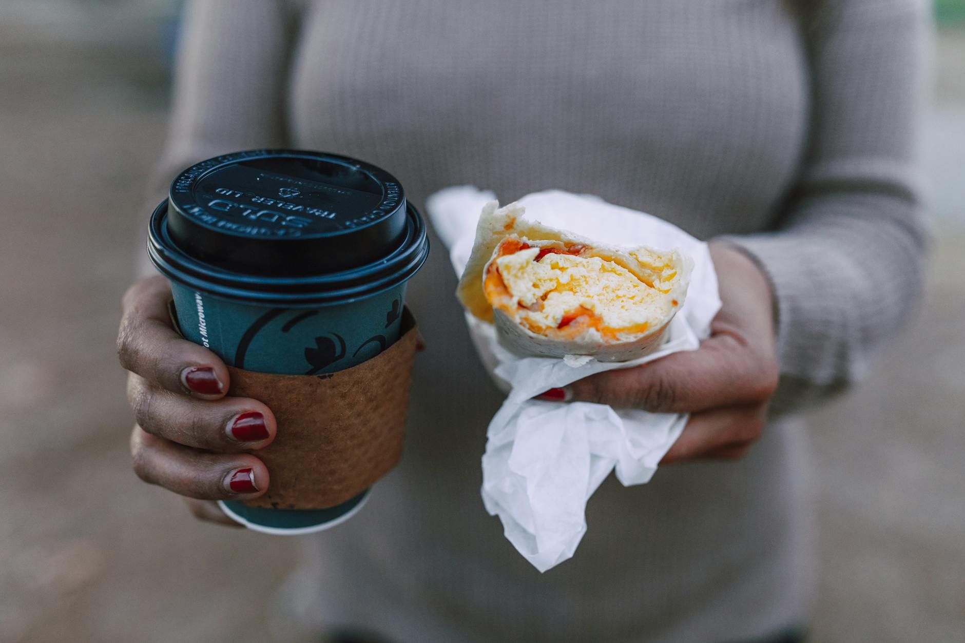 Person Holding Delicious Sandwich and Coffee Drink