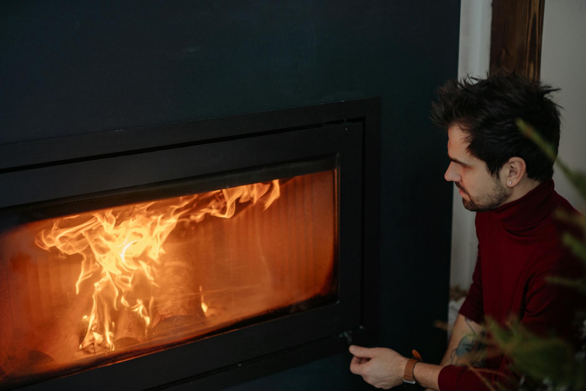 Man in Red Long Sleeves Sitting Near a Fireplace