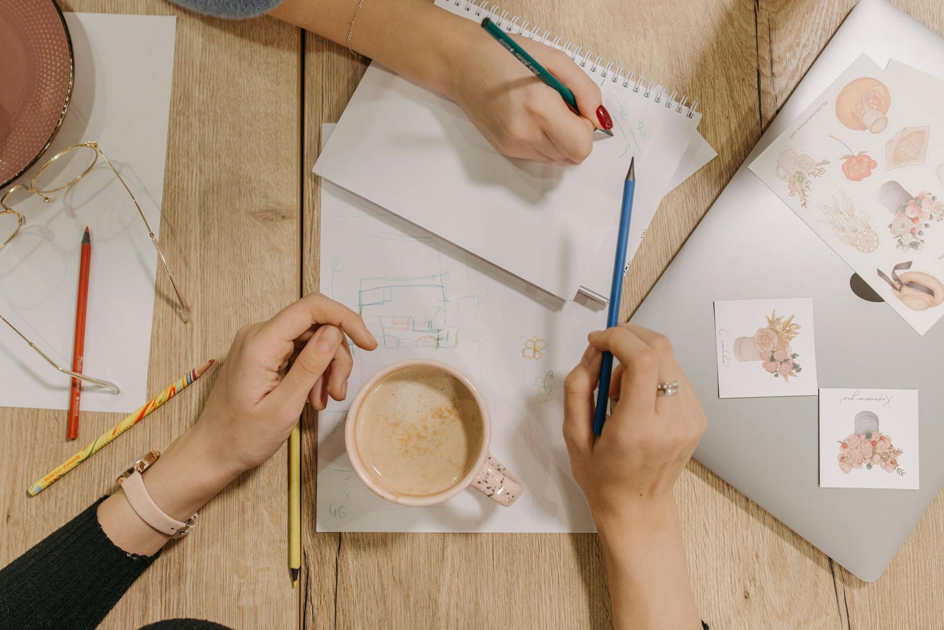 People Holding Pencils while Writing on White Paper