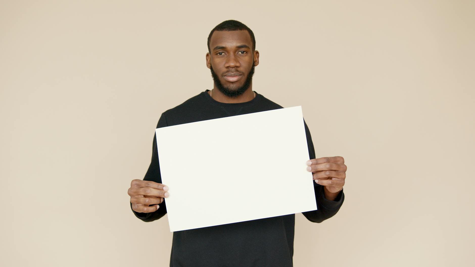 Man in black shirt holding white paper