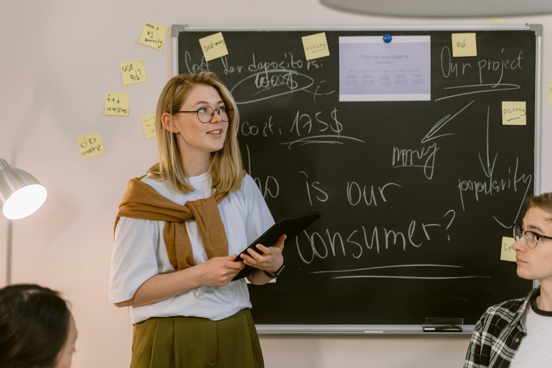 A Woman in White Shirt Standing Near the Chalkboard