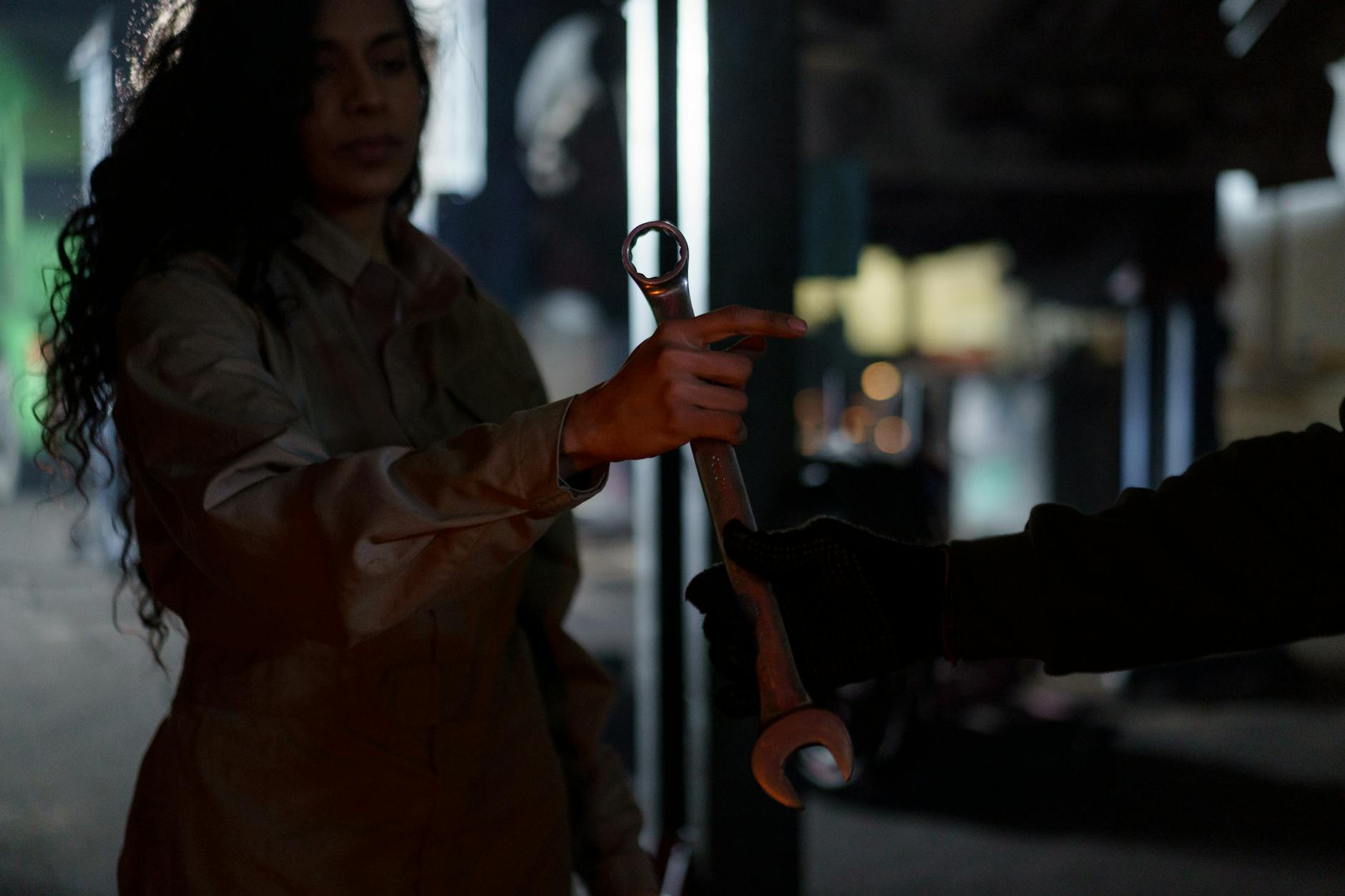 A hand holding a wrench against an oil rig