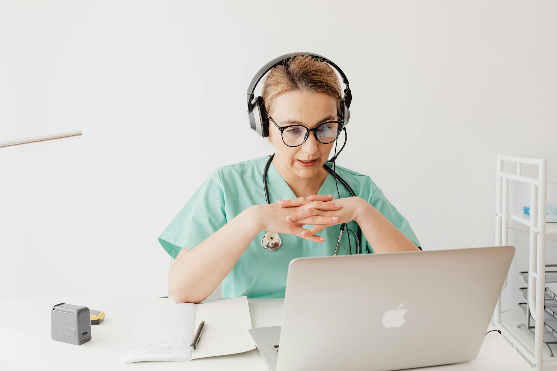 Woman in Scrub Suit Sitting In Front of a Laptop on a Video Call