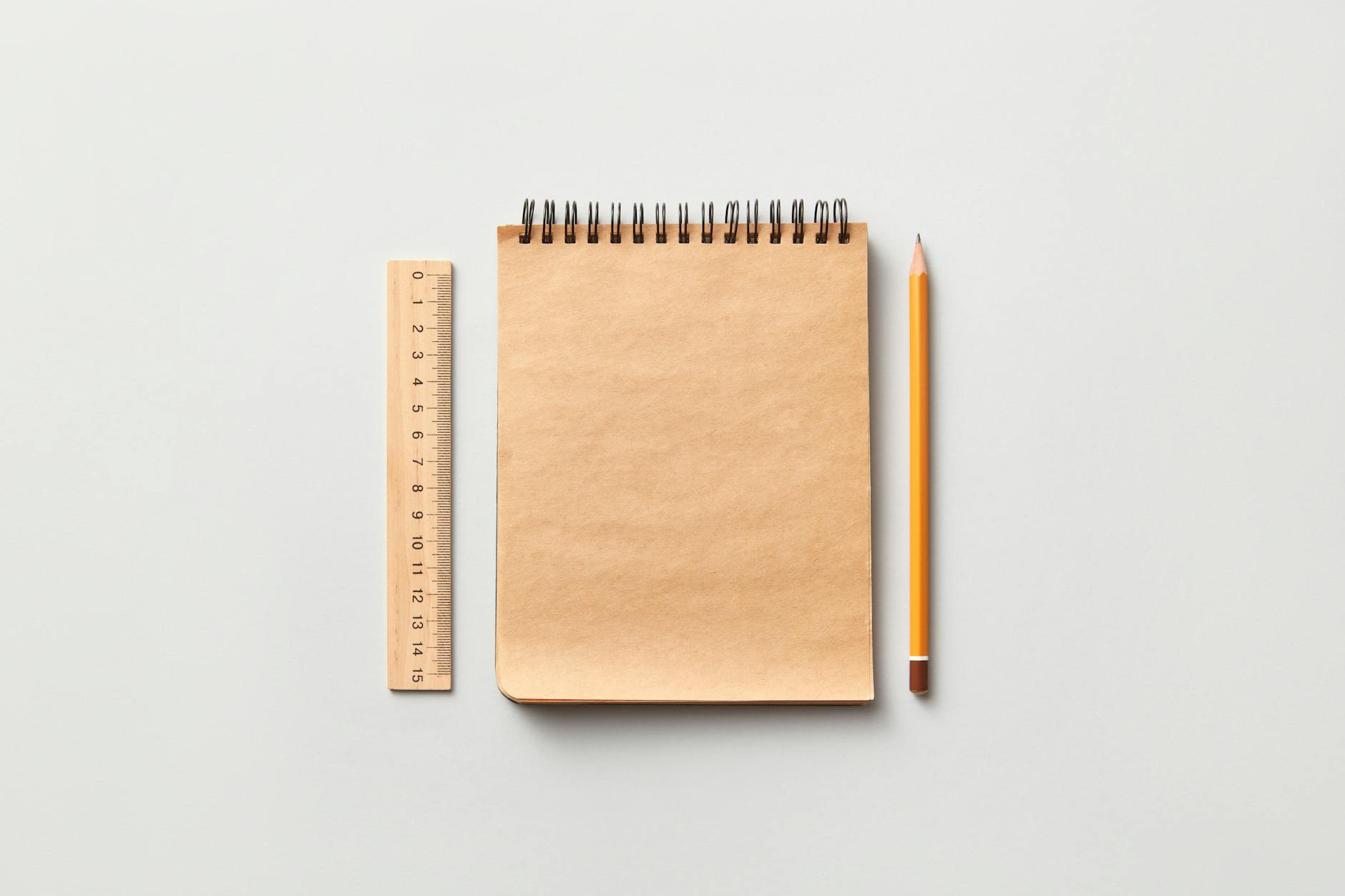 Pencil and Ruler beside Brown Spiral Notebook