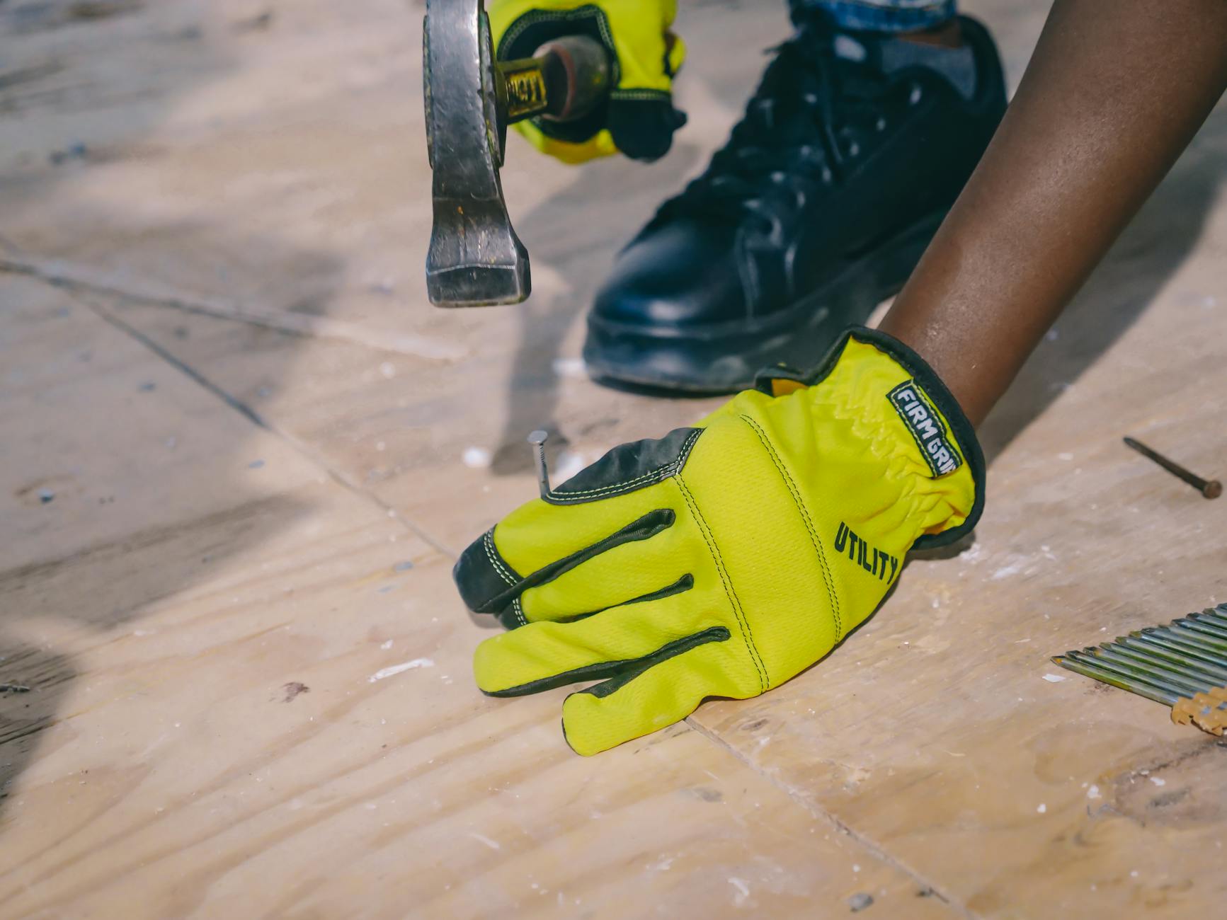 Person Hammering Nail on a Wooden Surface