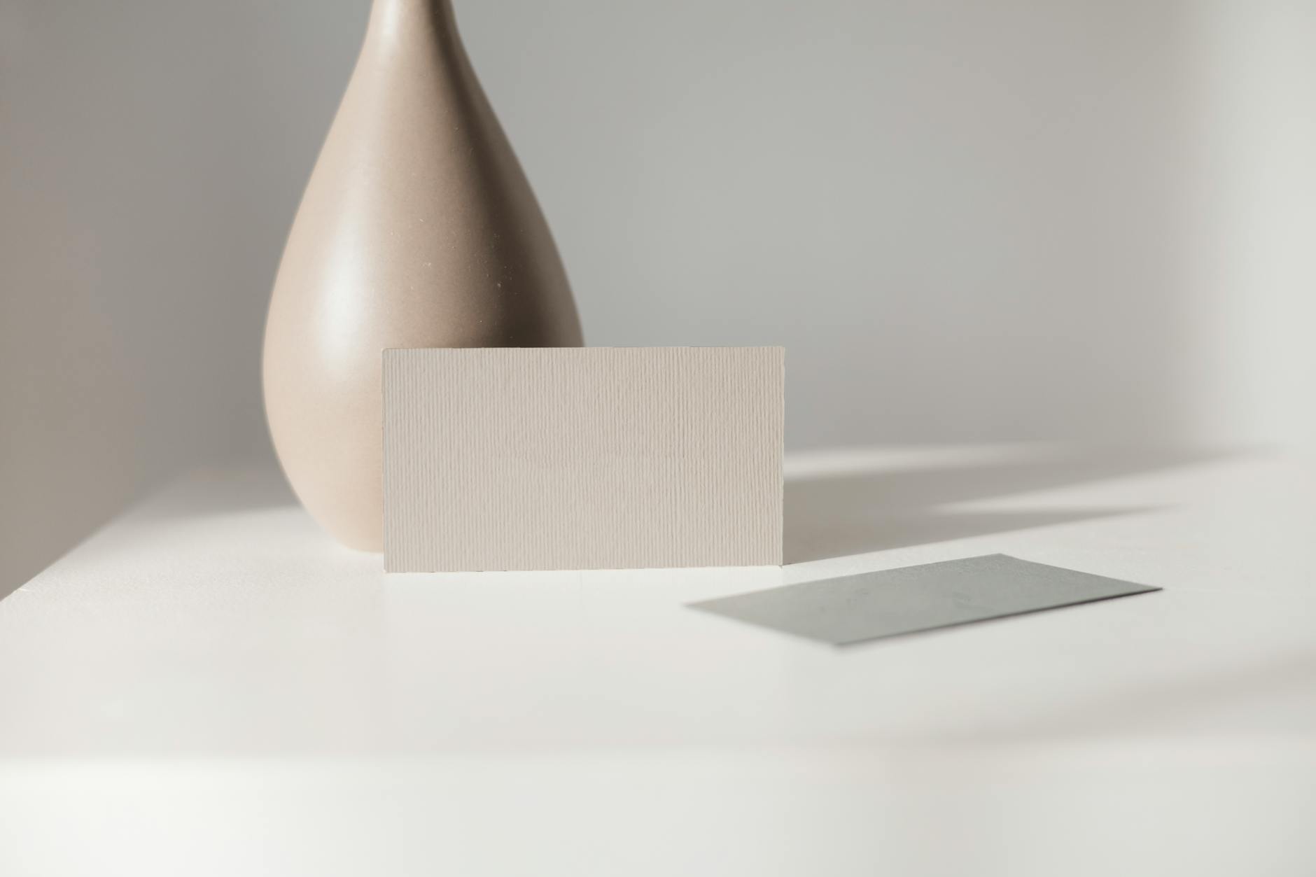 Brown Ceramic Vase and Blank Paper on a White Table