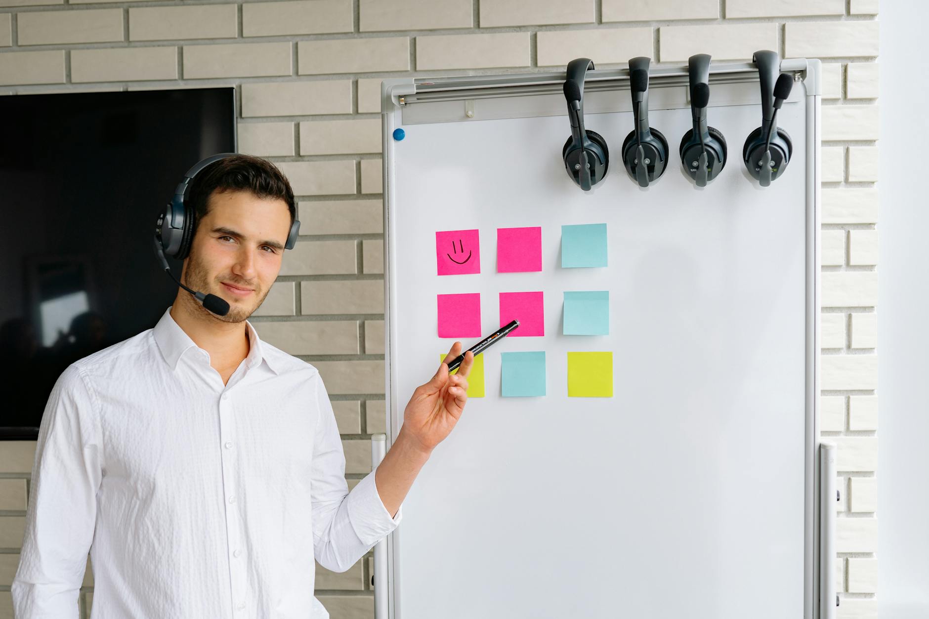 Man Wearing Headset Standing next to a White Board