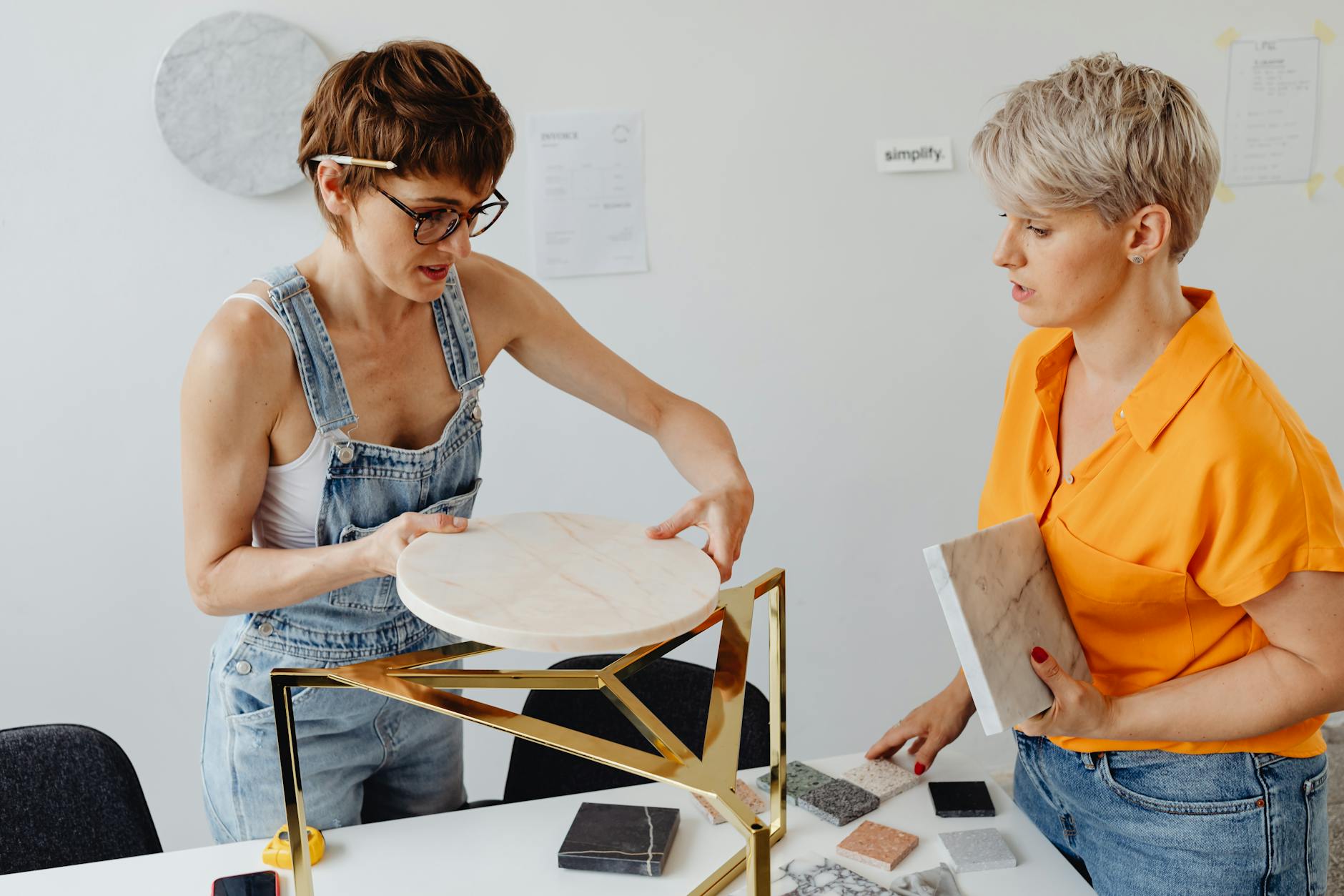 Woman in Blue Denim Jumpsuit Holding White Round Marble