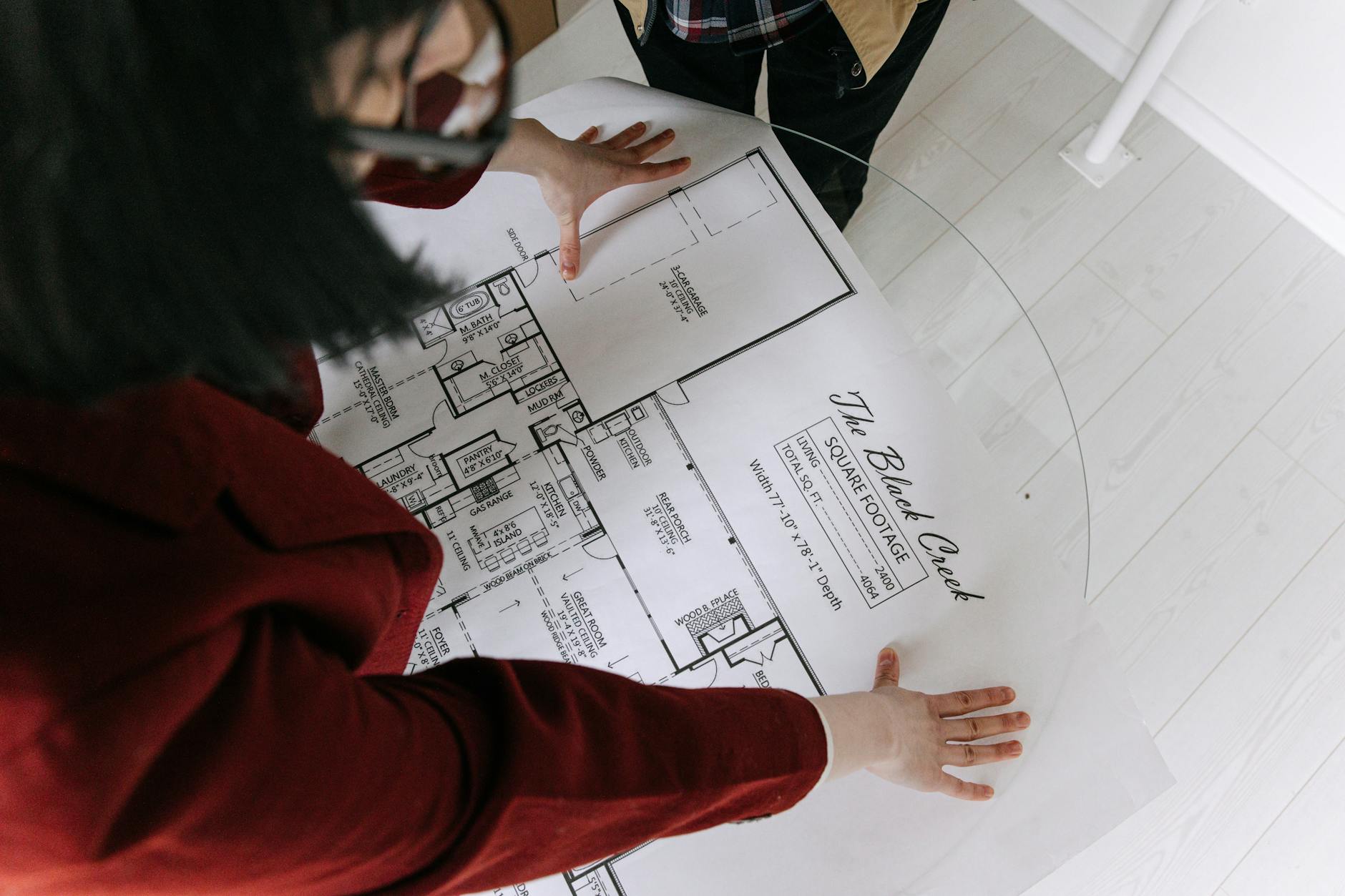 Woman Looking at House's Blueprint on Glass Table