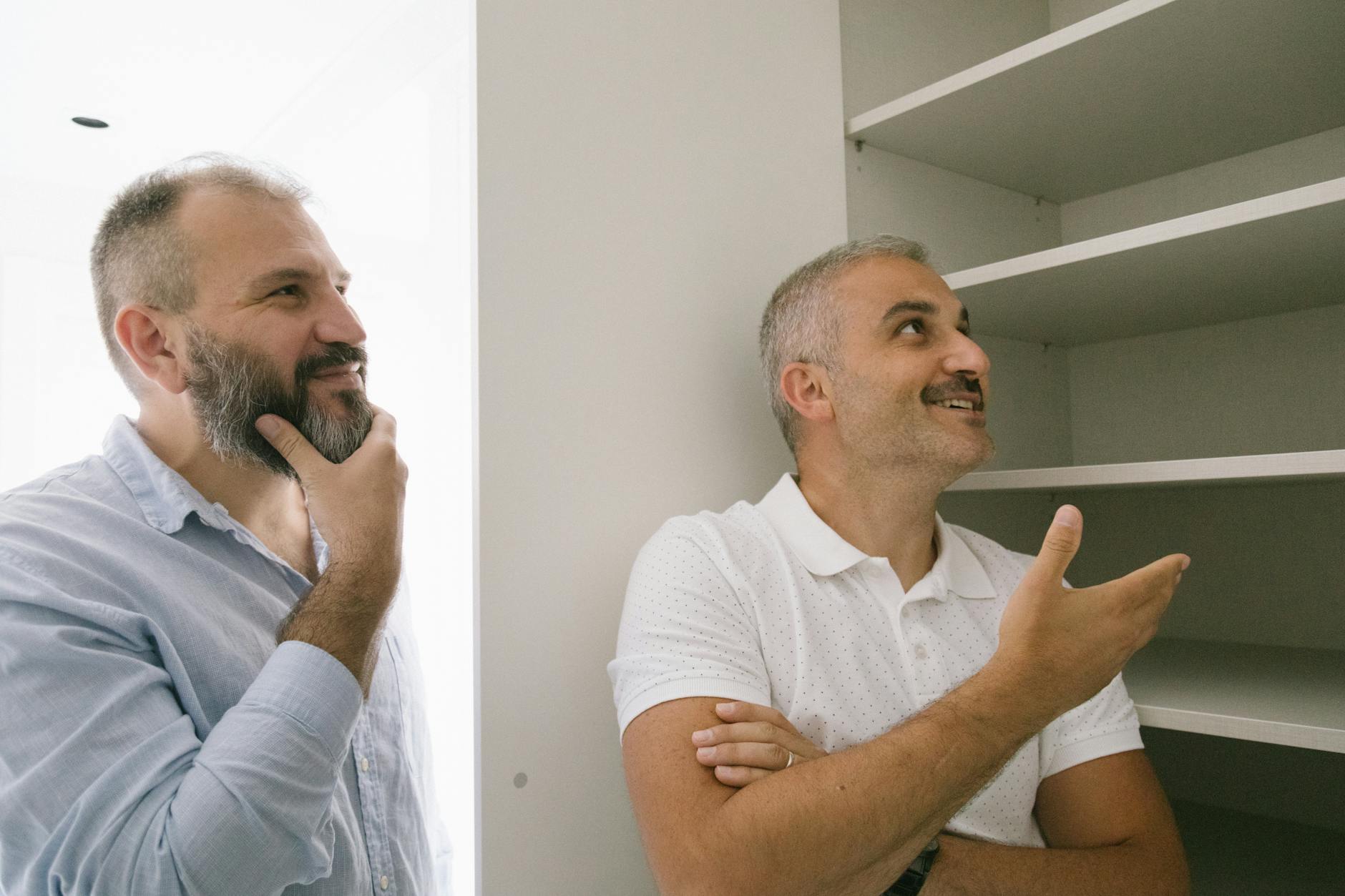 Men Looking at the Wooden Cabinet while Having a Conversation