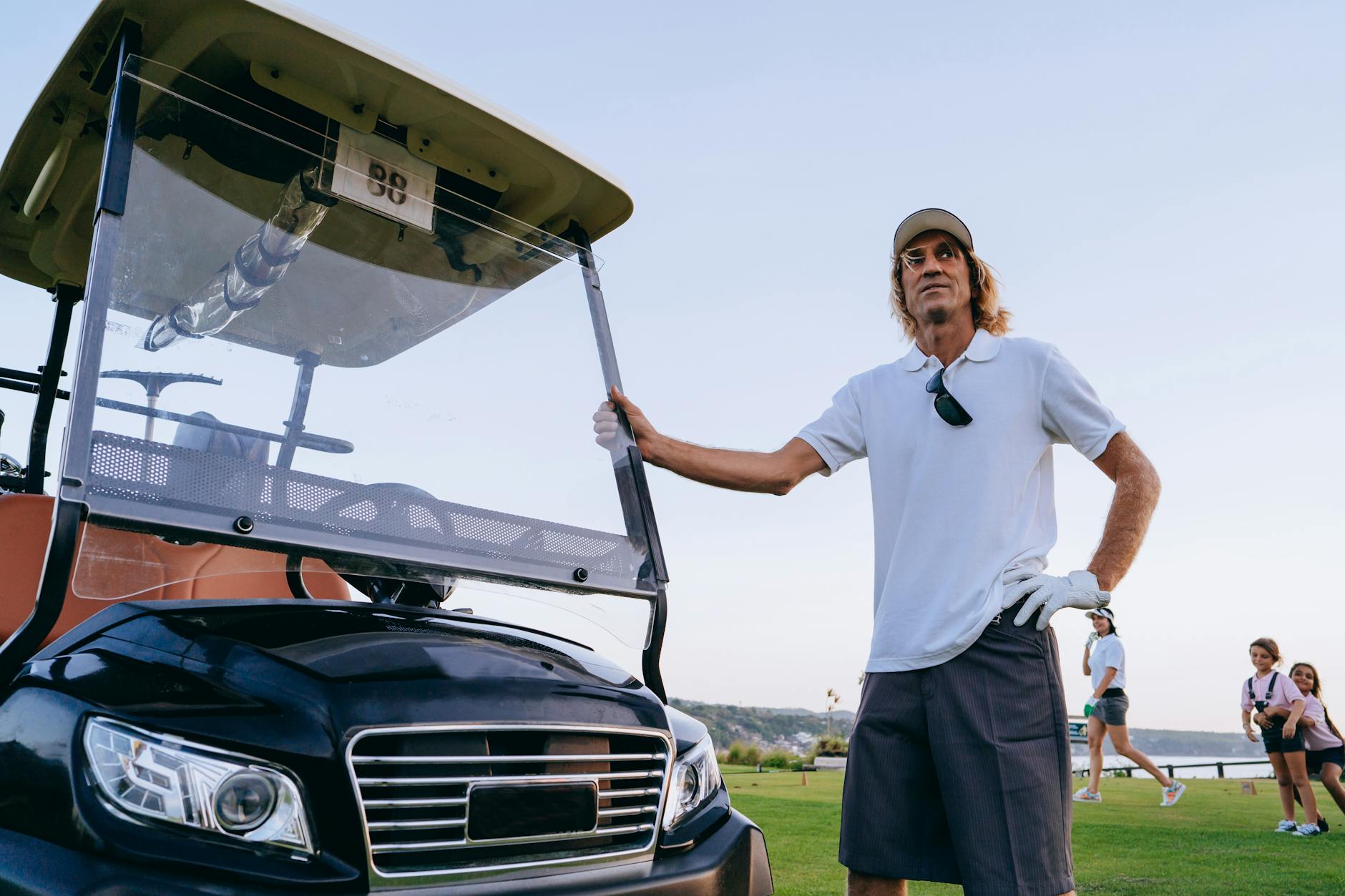 Man in White Polo Shirt standing beside Golf Cart